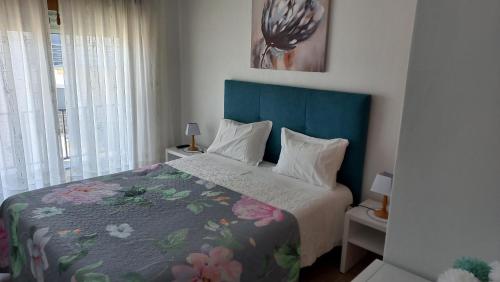 een slaapkamer met een bed met een blauw hoofdeinde bij Casa Luar in Odeceixe