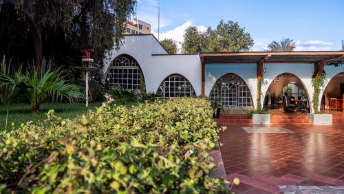 une cour avec un bâtiment blanc orné d'arches et de plantes dans l'établissement Sirikwa Hotel, à Eldoret