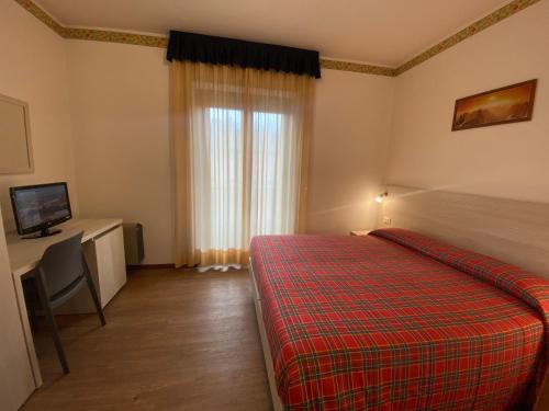 una camera con letto, scrivania e finestra di Hotel International a Tarvisio