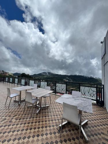 un ensemble de tables et de chaises sur un balcon dans l'établissement Summer Dreams Cottage Kodaikanal, à Kodaikānāl