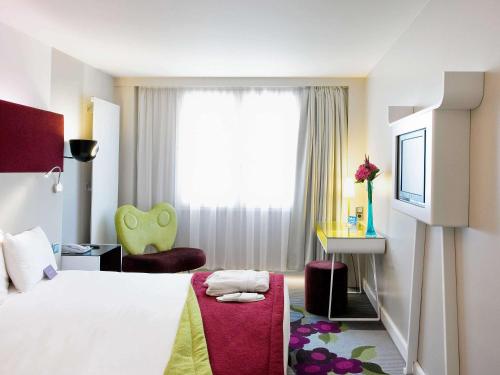 um quarto de hotel com uma cama e uma cadeira em Mercure Paris Bercy Bibliothèque em Paris