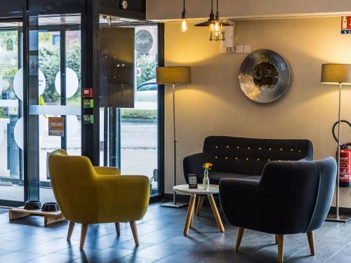 eine Lobby mit einem Sofa, Stühlen und einem Tisch in der Unterkunft Novotel Suites Rouen Normandie in Rouen