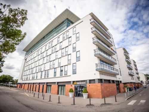 ein großes weißes Gebäude in einer Stadtstraße in der Unterkunft Novotel Suites Rouen Normandie in Rouen