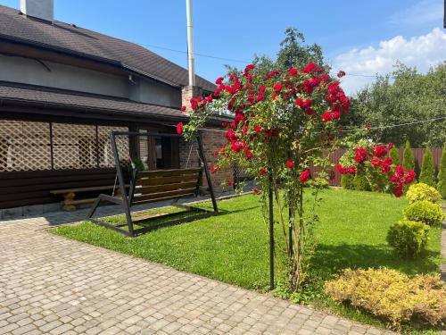 un arbusto con flores rojas junto a un banco en Артемів двір, en Slavske