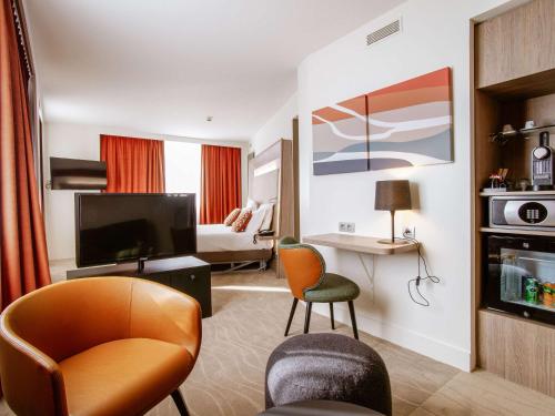 a hotel room with a living area with a television at Novotel Lyon Centre-Confluence Bord de Saone in Lyon