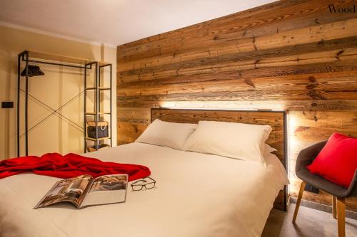 een slaapkamer met een wit bed en een houten muur bij Apartments Les Crouses in Valtournenche