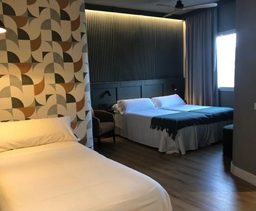 een hotelkamer met 2 bedden en een stoel bij Nuria in Tarragona