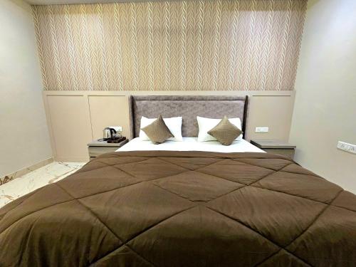 1 dormitorio con 1 cama grande con manta y almohadas marrones en Zipcode Stay, en Agra