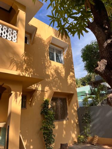 a yellow building with a tree in front of it at Zuri home in Watamu