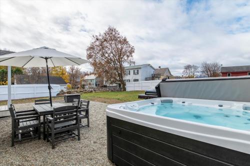 una vasca idromassaggio con tavolo, sedie e ombrellone di Updated Family-sized Home in Heart of Rutland, Near Slopes, EV Level 2, Hot Tub a Rutland