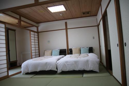 een slaapkamer met een groot bed met witte lakens en blauwe kussens bij Miyajima Hotel New Kotobuki in Miyajima