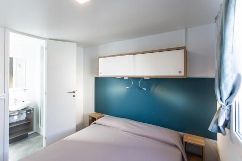 1 dormitorio con 1 cama con pared azul en Camping Marelago, en Caorle