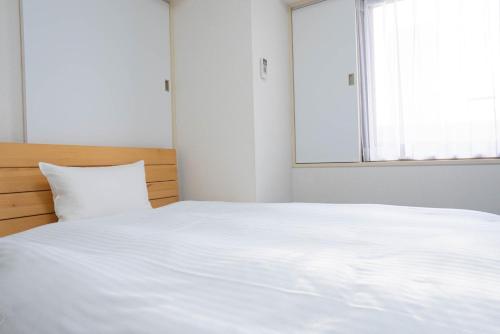 - un lit blanc dans une chambre avec fenêtre dans l'établissement Hotel Alpha Inn Akita - Vacation STAY 67278v, à Akita