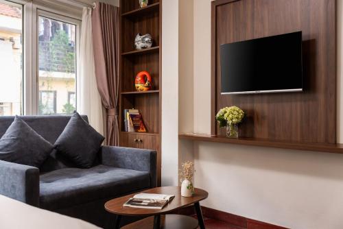 a living room with a couch and a tv on a wall at Charlie House Hanoi in Hanoi