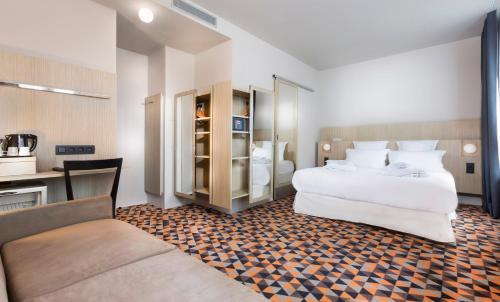 Habitación de hotel con 2 camas y sofá en Libertel Gare Du Nord Suede, en París