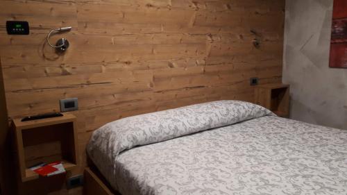 1 dormitorio con 1 cama y pared de madera en B&B Corte Rossa, en Tirano