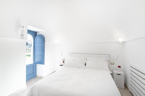 a white bedroom with a blue door and a bed at Borgofreddo Luxury Suite in Monopoli