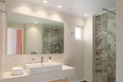 a white bathroom with a sink and a mirror at High Beach Resort in Malia