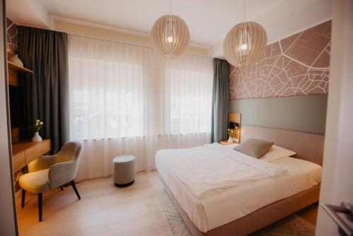 a bedroom with a bed and a chair and chandeliers at Hotel-Restaurant Haselhoff in Coesfeld