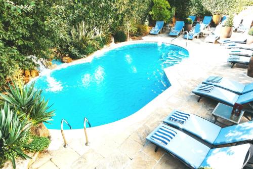 a swimming pool with blue lounge chairs in a yard at The Club Hotel & Spa Jersey in Saint Helier Jersey