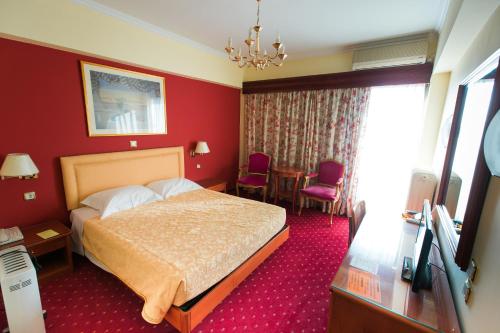 a hotel room with a bed and red walls at Grand Hotel in Larisa