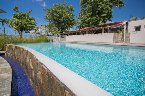 una piscina con parete di mantenimento accanto a una piscina di Courbaril Hôtel a Les Trois-Îlets