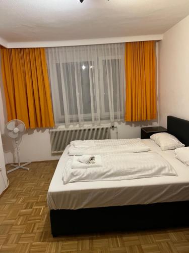 - une chambre avec 2 lits et des rideaux orange dans l'établissement City Appartement 4600, à Wels