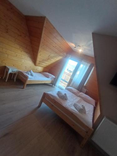 Cette chambre mansardée comprend 2 lits et une fenêtre. dans l'établissement Tatrzańska Rezydencja pod Brzyzkiem, à Zakopane