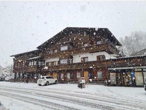 een met sneeuw bedekt gebouw met een auto voor het gebouw bij Chalet Helen in Arabba