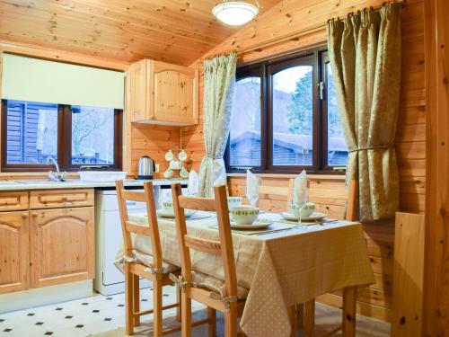 een keuken met een tafel, stoelen en ramen bij Fern Lodge- Burnside Park in Keswick