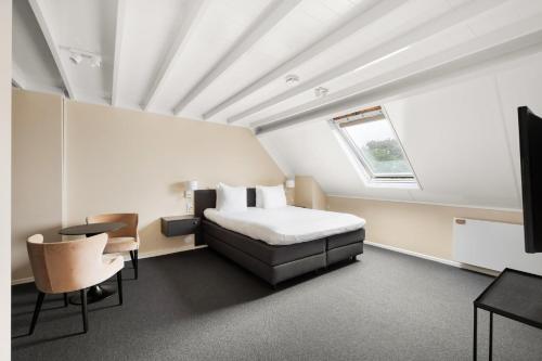 Schlafzimmer mit einem Bett, einem Tisch und einem Fenster in der Unterkunft De Lijsterhof in Domburg