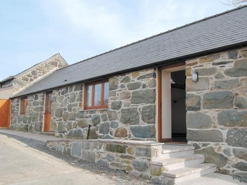 - un bâtiment en pierre avec une porte et des escaliers extérieurs dans l'établissement The Barn, à Talsarnau