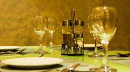 a table with four wine glasses and plates on it at City Park Hotel Apartments in Muscat