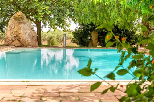 uma piscina azul com árvores ao fundo em Agri Resort San Giuliano em Santa Maria la Palma