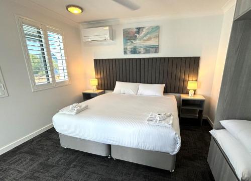 um quarto com uma grande cama branca e 2 candeeiros em Palace Hotel Proserpine em Proserpine