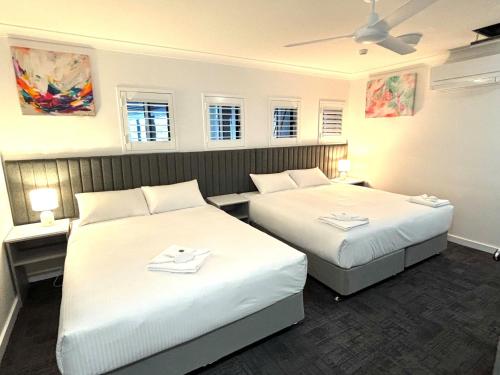 um quarto de hotel com duas camas e duas mesas em Palace Hotel Proserpine em Proserpine