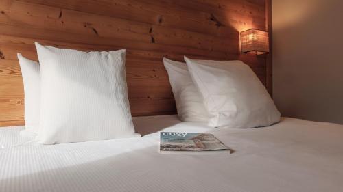 uma cama com almofadas brancas e uma revista em Hôtel Lyret em Chamonix-Mont-Blanc