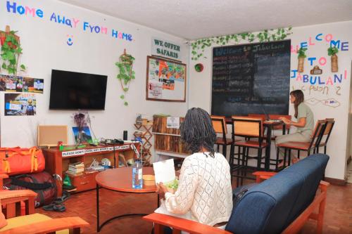 dos personas sentadas en mesas en una cafetería en Jabulani Nairobi Backpackers Hostel, en Nairobi