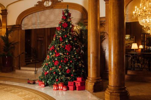 Un árbol de Navidad en un vestíbulo con regalos rojos en Hôtel Barrière Le Normandy, en Deauville