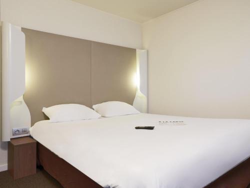 a bedroom with a large white bed with two pillows at Campanile Troyes Sud - Buchères in Troyes