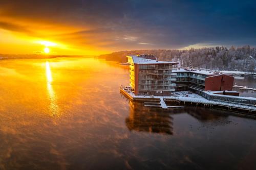 ein Gebäude auf dem Wasser mit Sonnenuntergang im Hintergrund in der Unterkunft Hotel Mikołajki Leisure & SPA - Destigo Hotels in Mikołajki