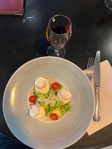 um prato branco com uma salada e um copo de vinho em Hotel Duchesse Anne em Dinan