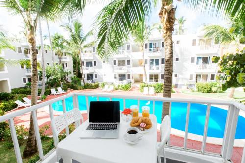 - une table avec un ordinateur portable sur un balcon avec une piscine dans l'établissement FIESTA SOL CARIBE playa LOS CORALES, à Punta Cana