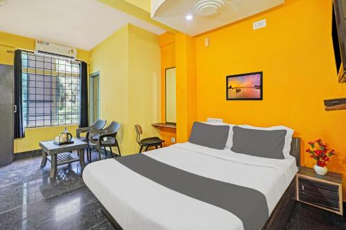 a bedroom with a large bed with yellow walls at Collection O Coorg formerly Hotel Aravind Premier in Madikeri