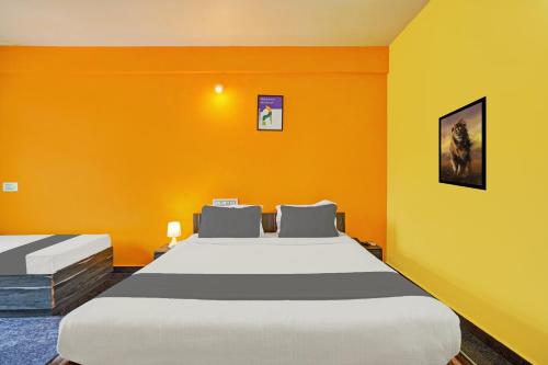 a bedroom with two beds with an orange wall at Collection O Coorg formerly Hotel Aravind Premier in Madikeri