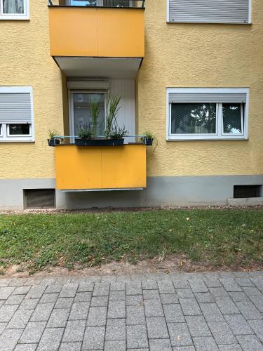 un edificio giallo con due piantagioni sul lato di Apartments Neckarsulm a Neckarsulm