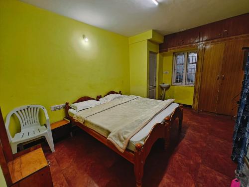 a bedroom with a bed and a chair in it at hilldown cottage in Ooty