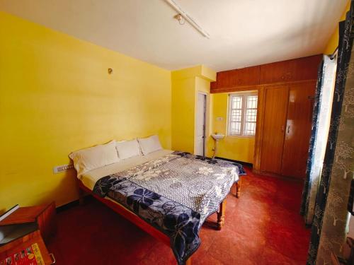 a bedroom with a bed in a room with yellow walls at hilldown cottage in Ooty