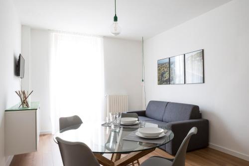 een eetkamer met een glazen tafel en een bank bij TorinoToStay Apartments in Turijn