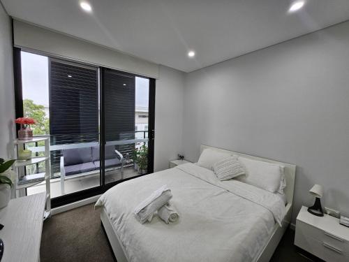 een witte slaapkamer met een groot bed met handdoeken erop bij Rouse Hills TownCentre luxury accommodation in Kellyville